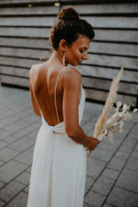 Brautfrisur mit hohem Dutt und Naturlocken mit glowy Brautmakeup